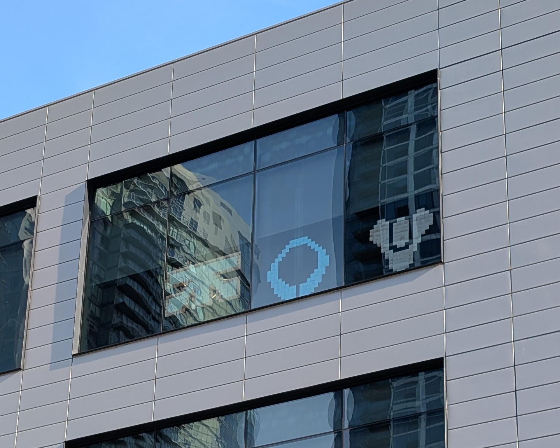 A long-distance shot taken of a window at Bungie's offices, featuring small glass art panels of the Traxus logo (Marathon), the Marathon logo, and the Destiny Tricorn logo. [Courtesy Reddit]