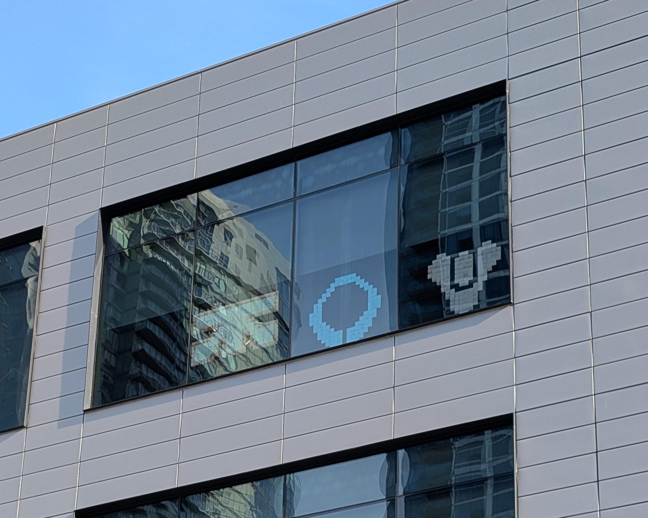 A long-distance shot taken of a window at Bungie's offices, featuring small glass art panels of the Traxus logo (Marathon), the Marathon logo, and the Destiny Tricorn logo. [Courtesy Reddit]