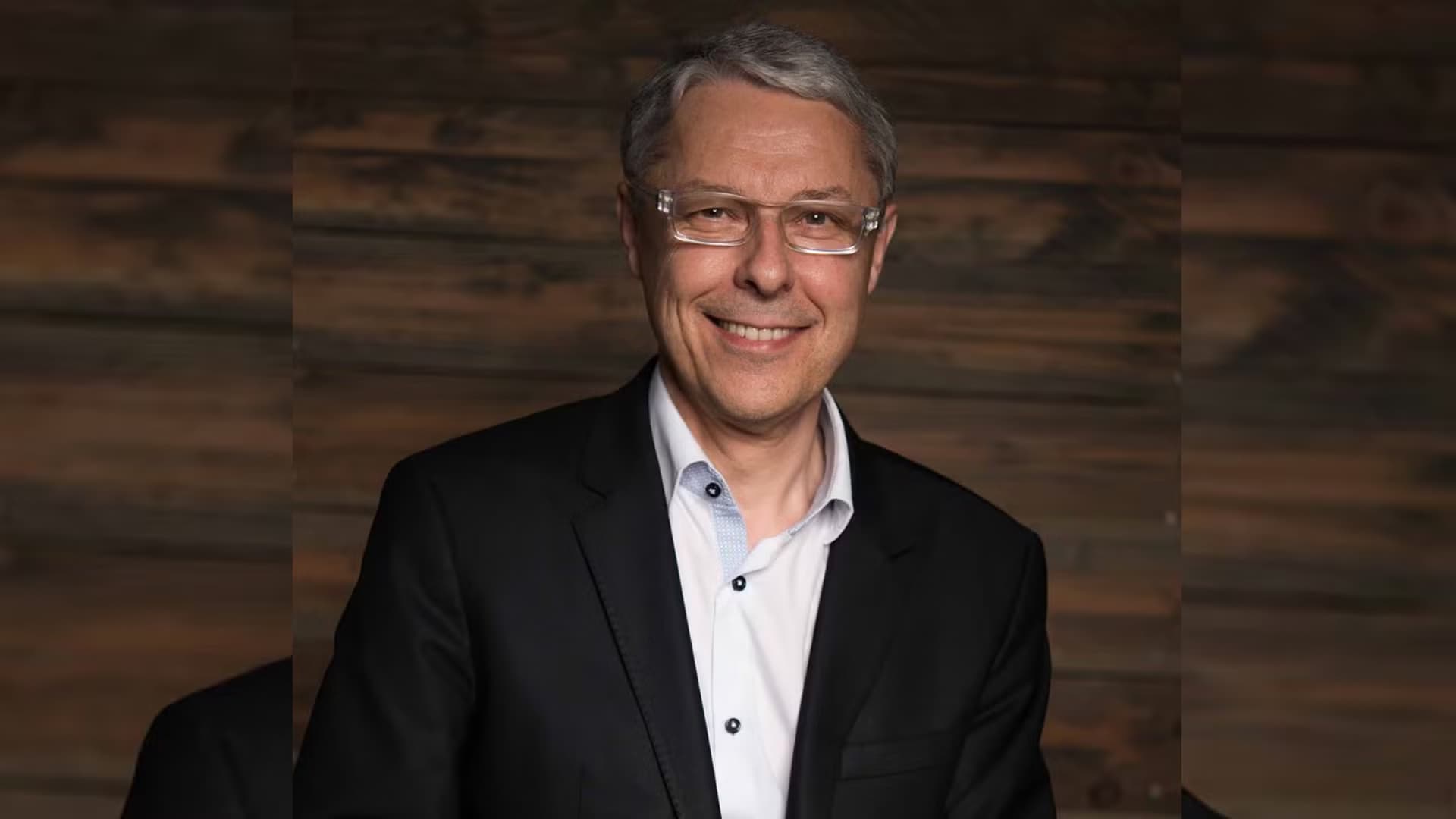 Claude Guillemot, co-founder of Ubisoft, standing over a wooden background.